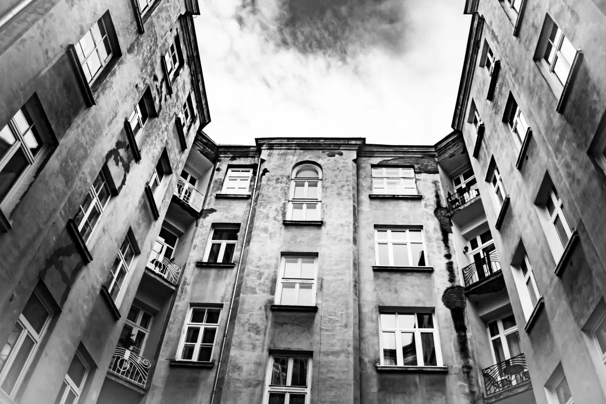 Black-and-white courtyard framed by weathered apartment walls and windows